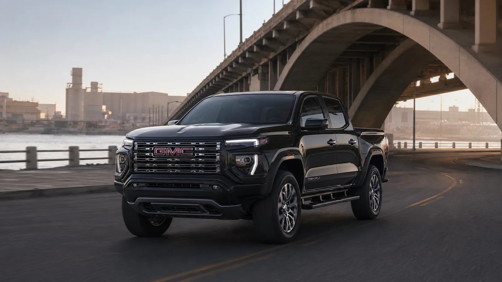 2026 GMC Canyon Denali driving beneath a concrete bridge at dawn - GMC Canyon