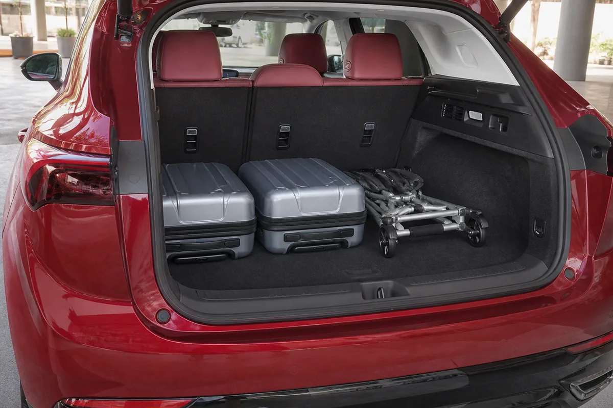 Buick Envision cargo area with rear seats upright, two carry-on cases, and a folded mobility walker