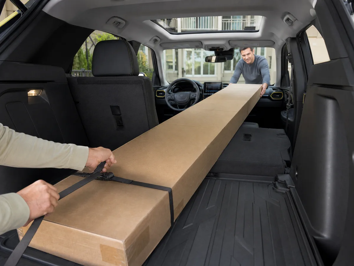 Long flat-pack box secured through the folded rear and front passenger seats of a Chevrolet Trailblazer