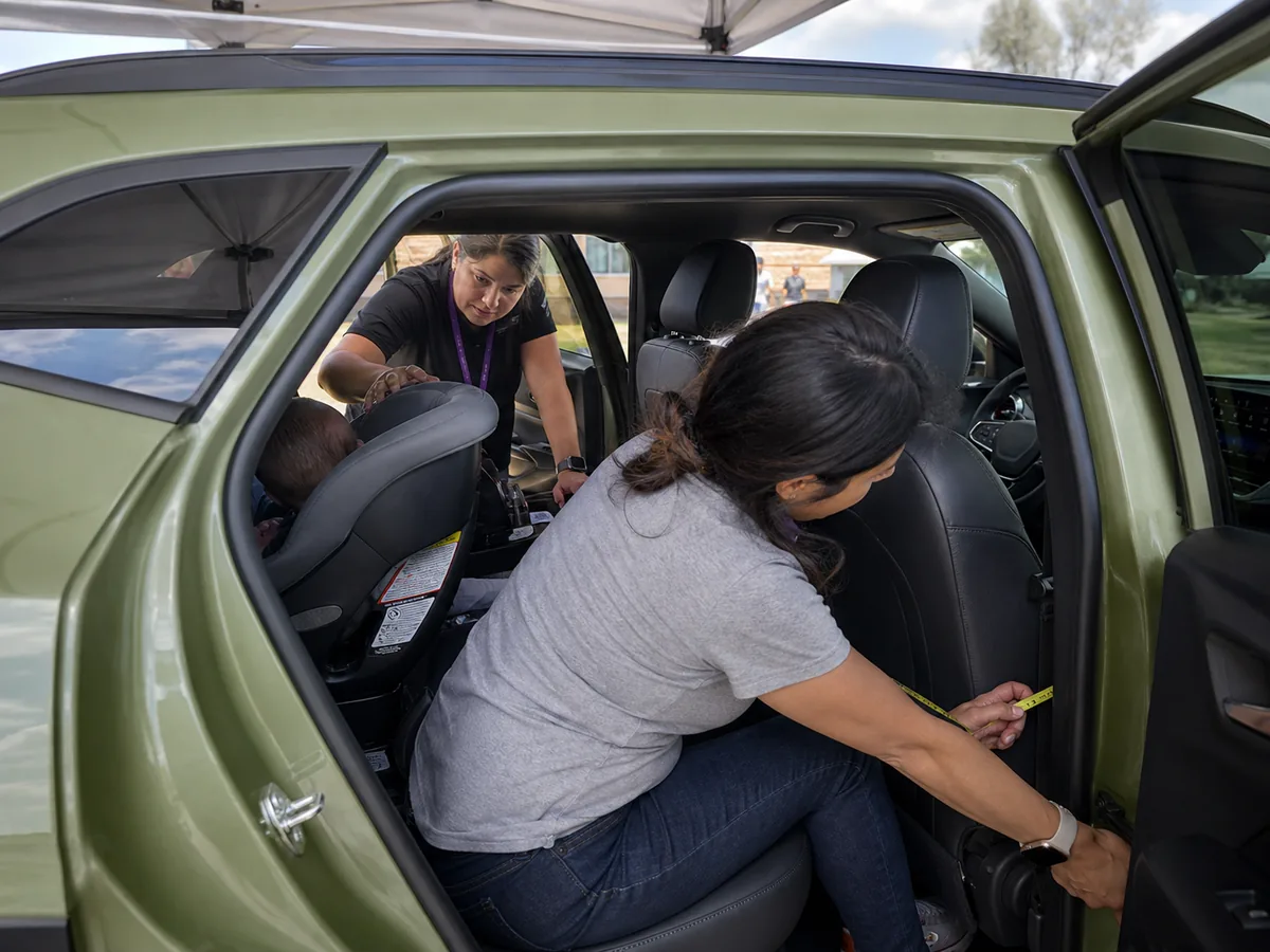 Child-seat technician checking a rear-facing restraint and passenger space inside a Chevrolet Trax