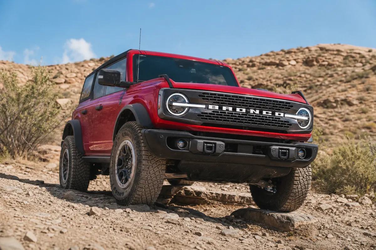 Ford Bronco parked at a legal trail entrance while the driver checks tire clearance and recovery points - Ford Bronco