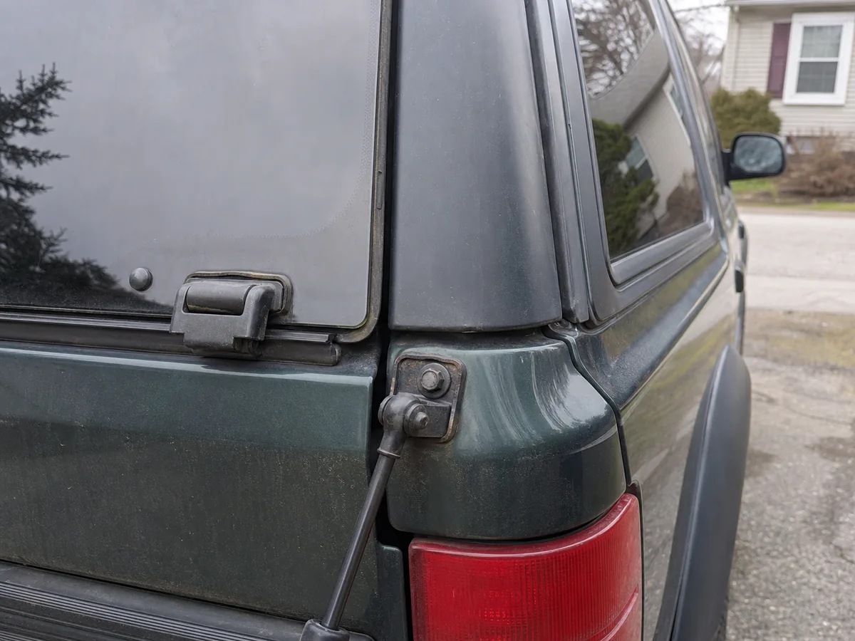 Rear liftgate glass hinge and strut bracket inspection on an early-2000s SUV - Ford Explorer