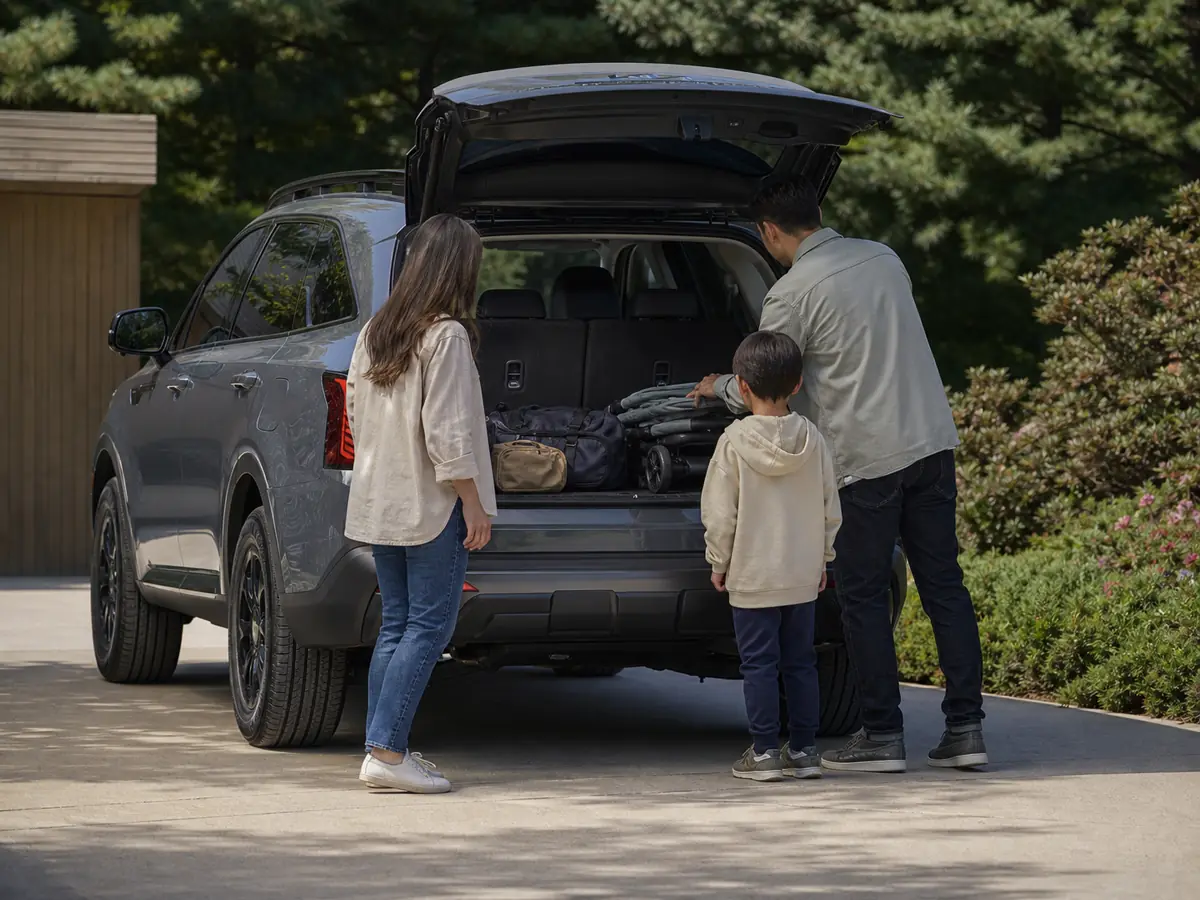 Family loading bags behind the raised third row of a Kia Sorento