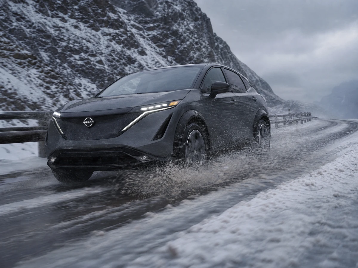 Nissan Ariya e-4ORCE driving through wet snow on an exposed mountain road with spray coming off the front wheels - Nissan Ariya