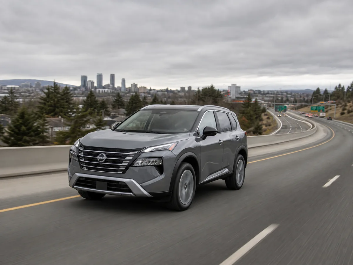 Nissan Rogue moving from city traffic toward an uphill highway merge
