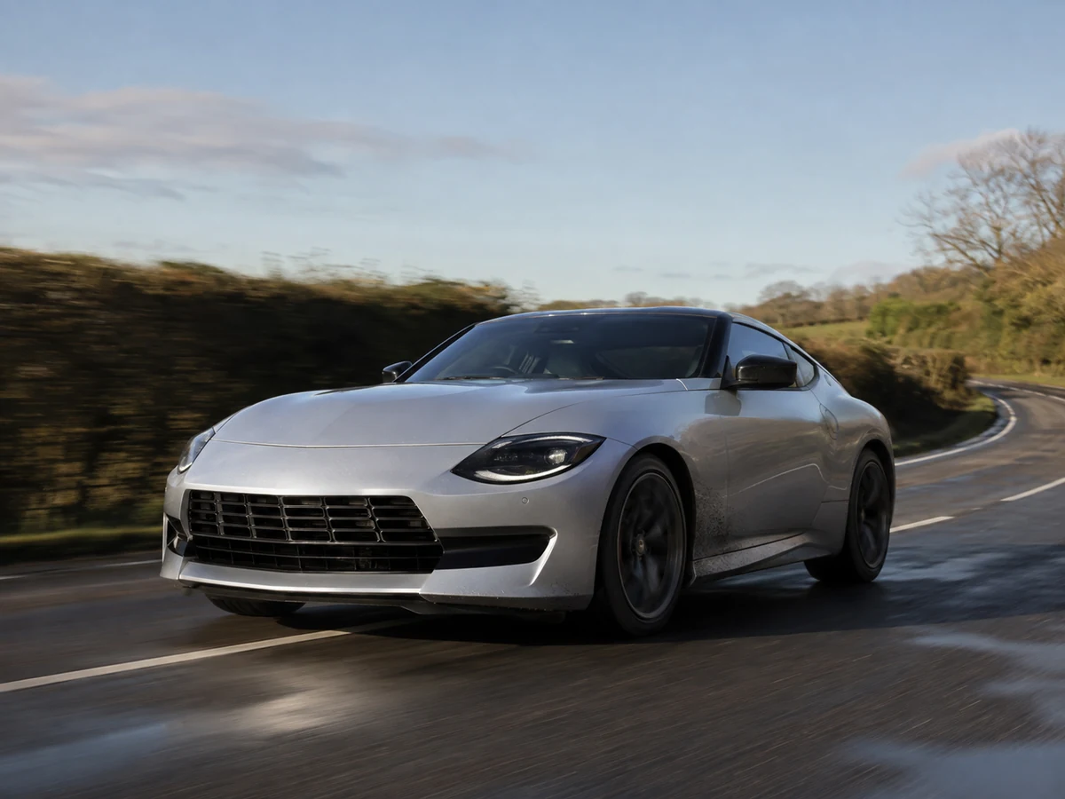 Nissan Z on a two-lane country road seen low from the front three-quarter with the long bonnet and low roofline in profile - Nissan Z