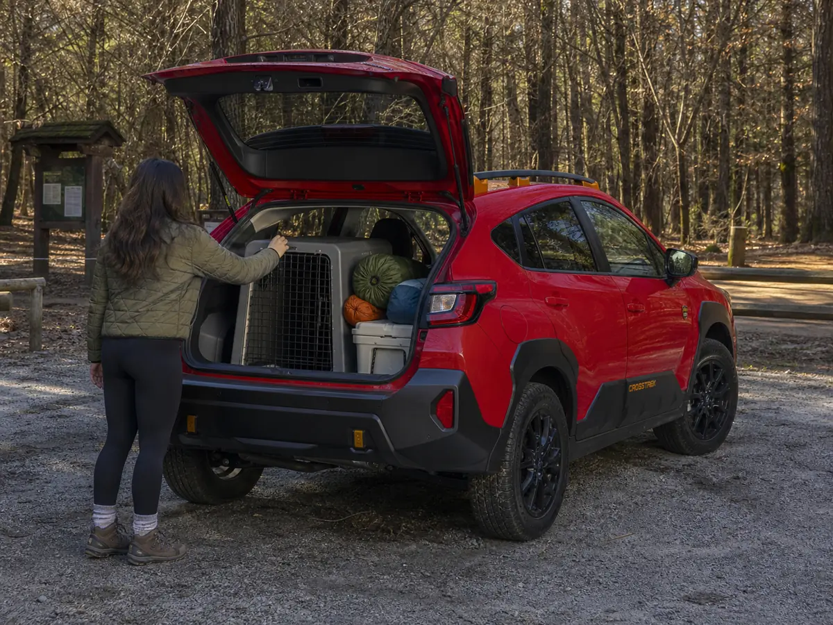 Dog crate and outdoor gear being loaded into a Subaru Crosstrek