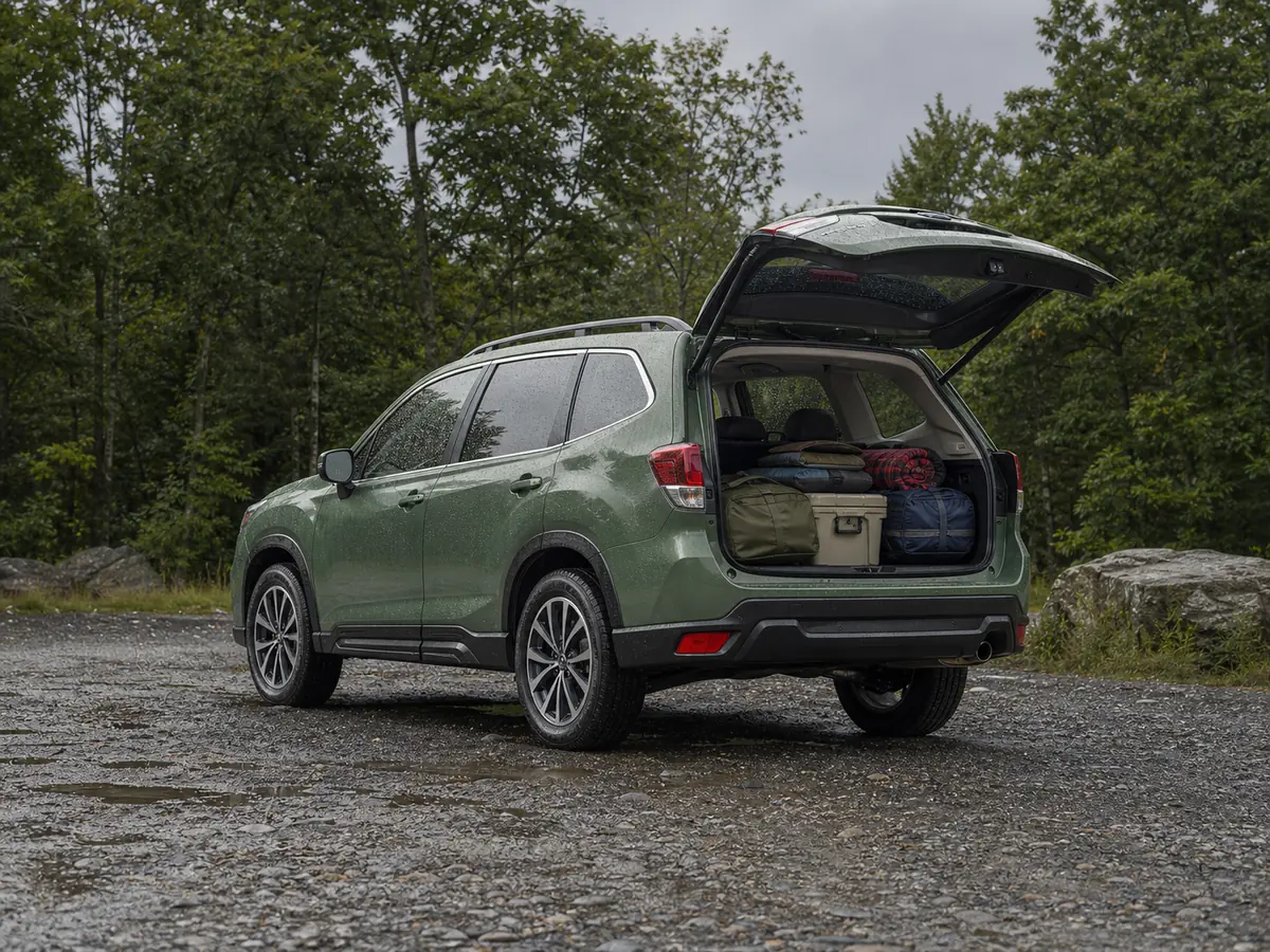 Green Subaru Forester loaded with outdoor gear at a wet trailhead with all four tires visible