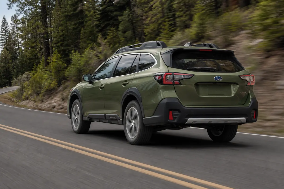 Subaru Outback climbing a dry mountain road in a low side-rear view