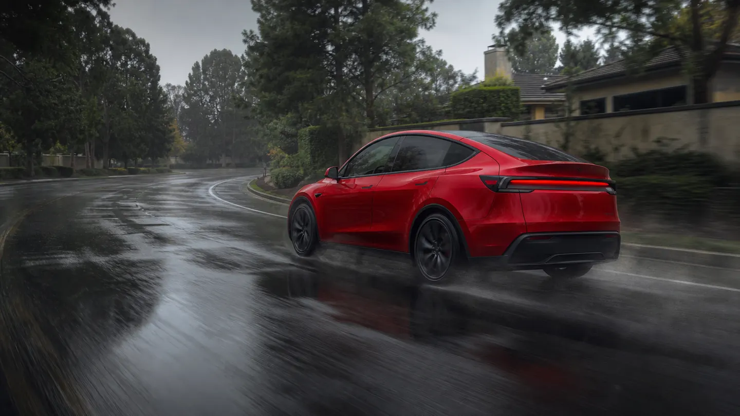 Tesla Model Y carrying passengers through a wet suburban curve