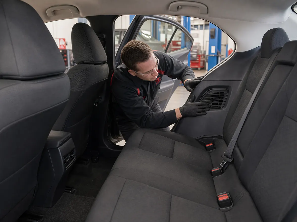 Technician checking the rear-seat hybrid battery cooling intake in a Toyota Corolla Hybrid - Toyota Corolla Hybrid