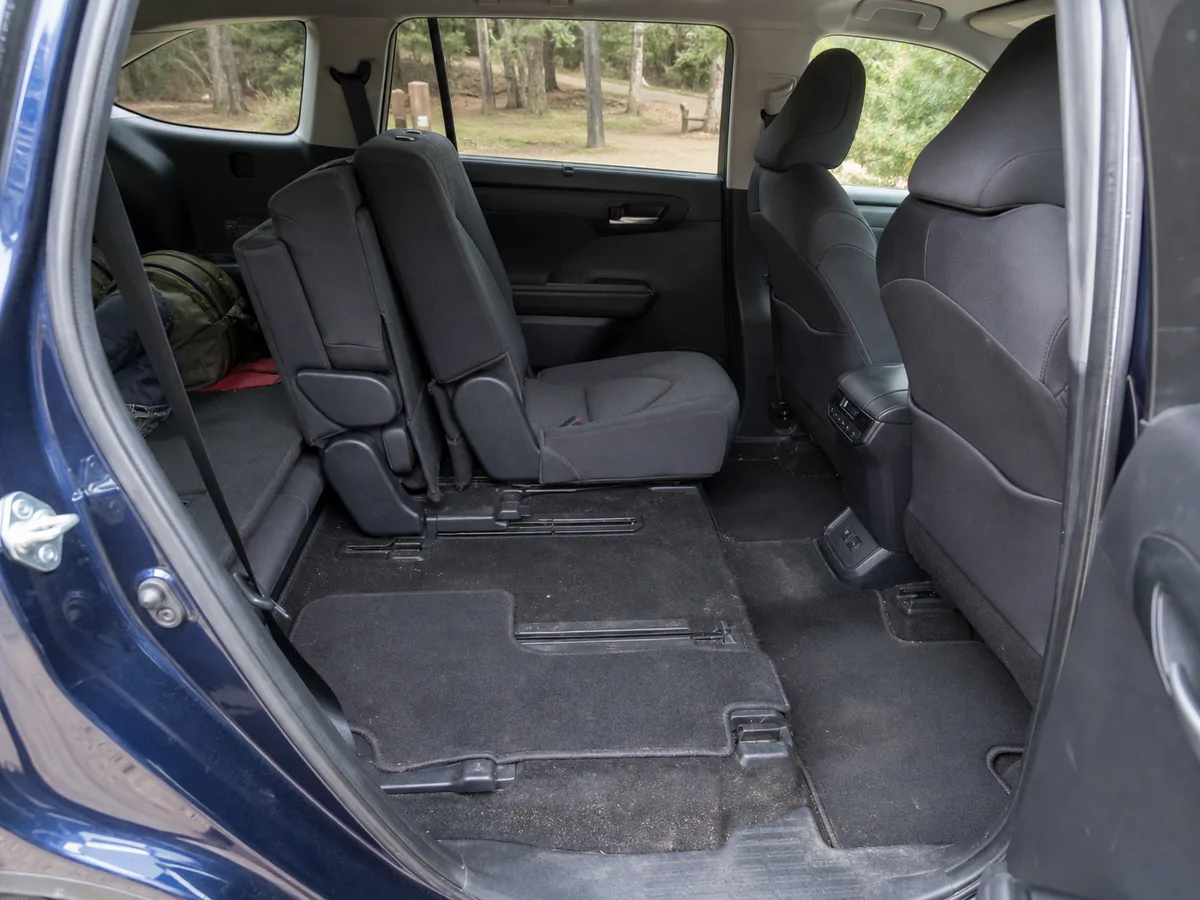 Three-row SUV cabin with second-row seat tracks, access path, and cargo wear visible