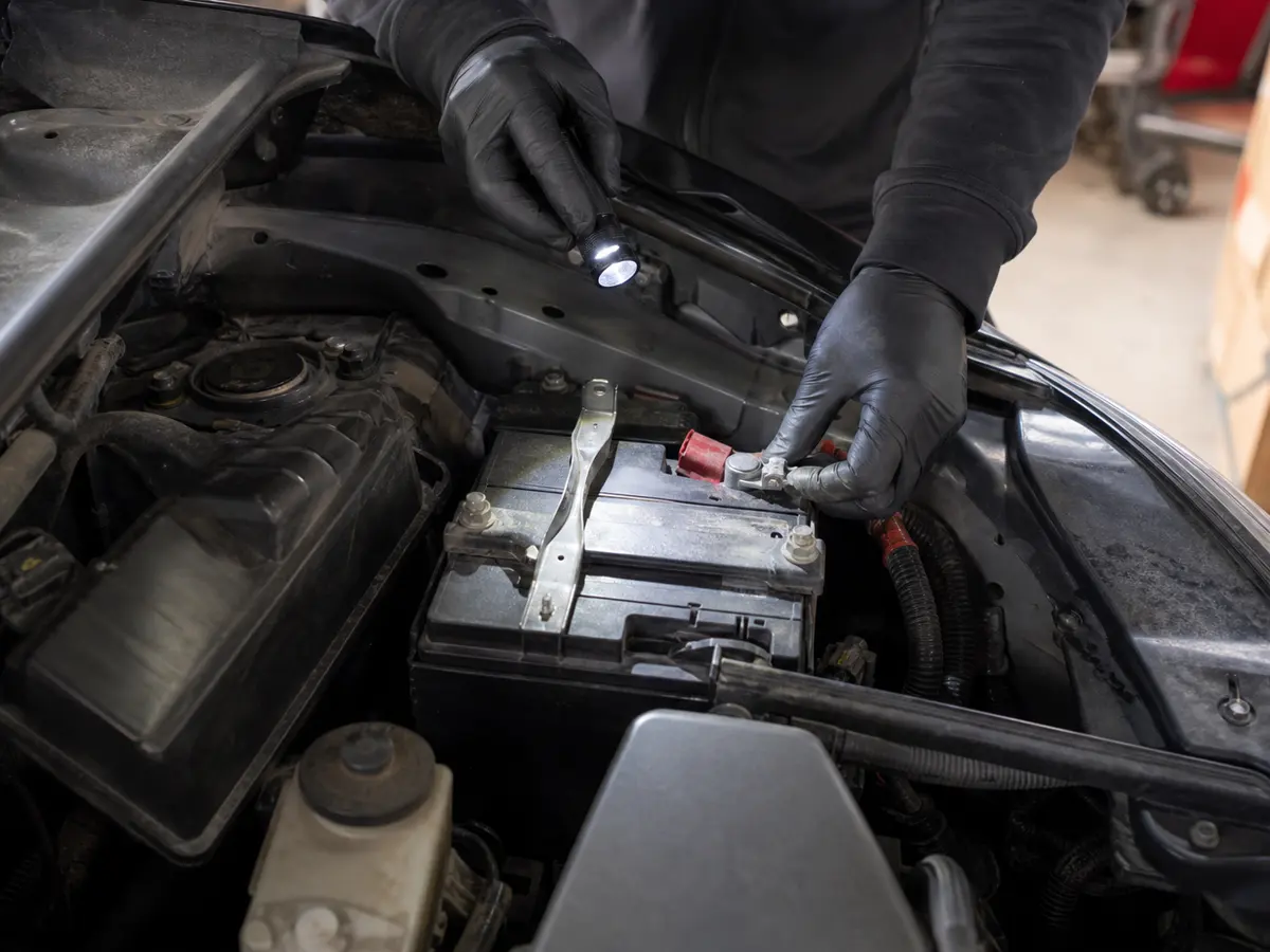 Technician checking a compact SUV battery hold-down during a used-car inspection - Toyota RAV4