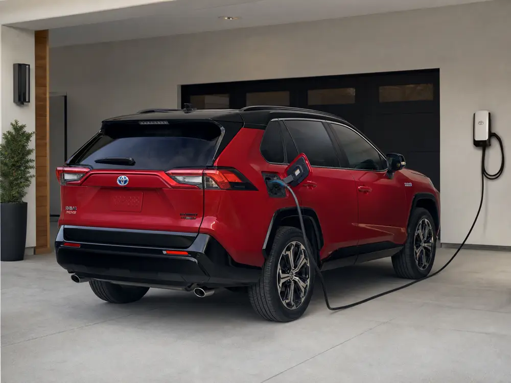 2024 Toyota RAV4 Prime charging in a home parking space with the cable kept clear of the walkway - Toyota RAV4 Prime